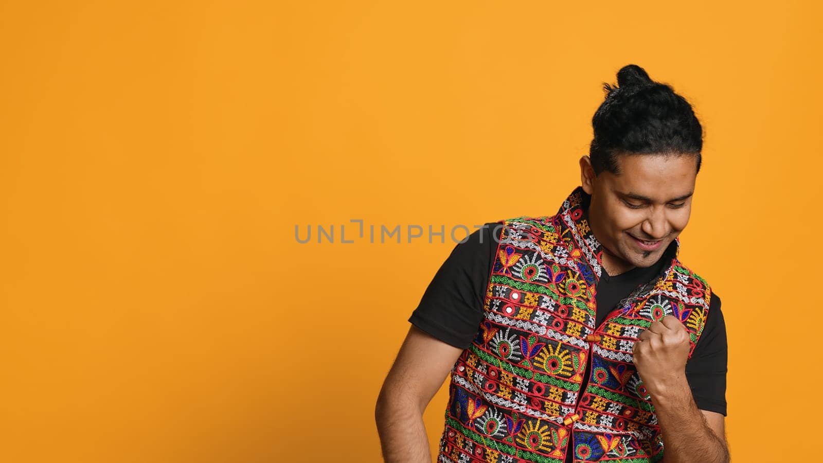 Portrait of narcissistic cheerful indian man celebrating and bragging, showing arrogance. Satisfied person boasting about achievement, cheering and gesticulating, studio background, camera A