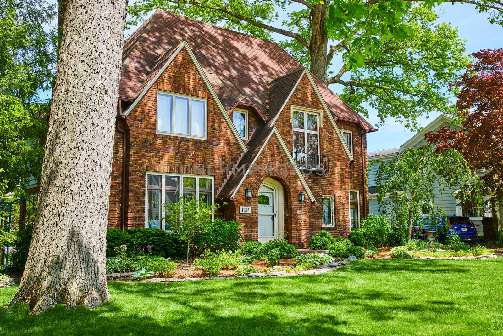 Traditional two-story brick house in Fort Wayne's historic South Wayne district, surrounded by lush greenery.