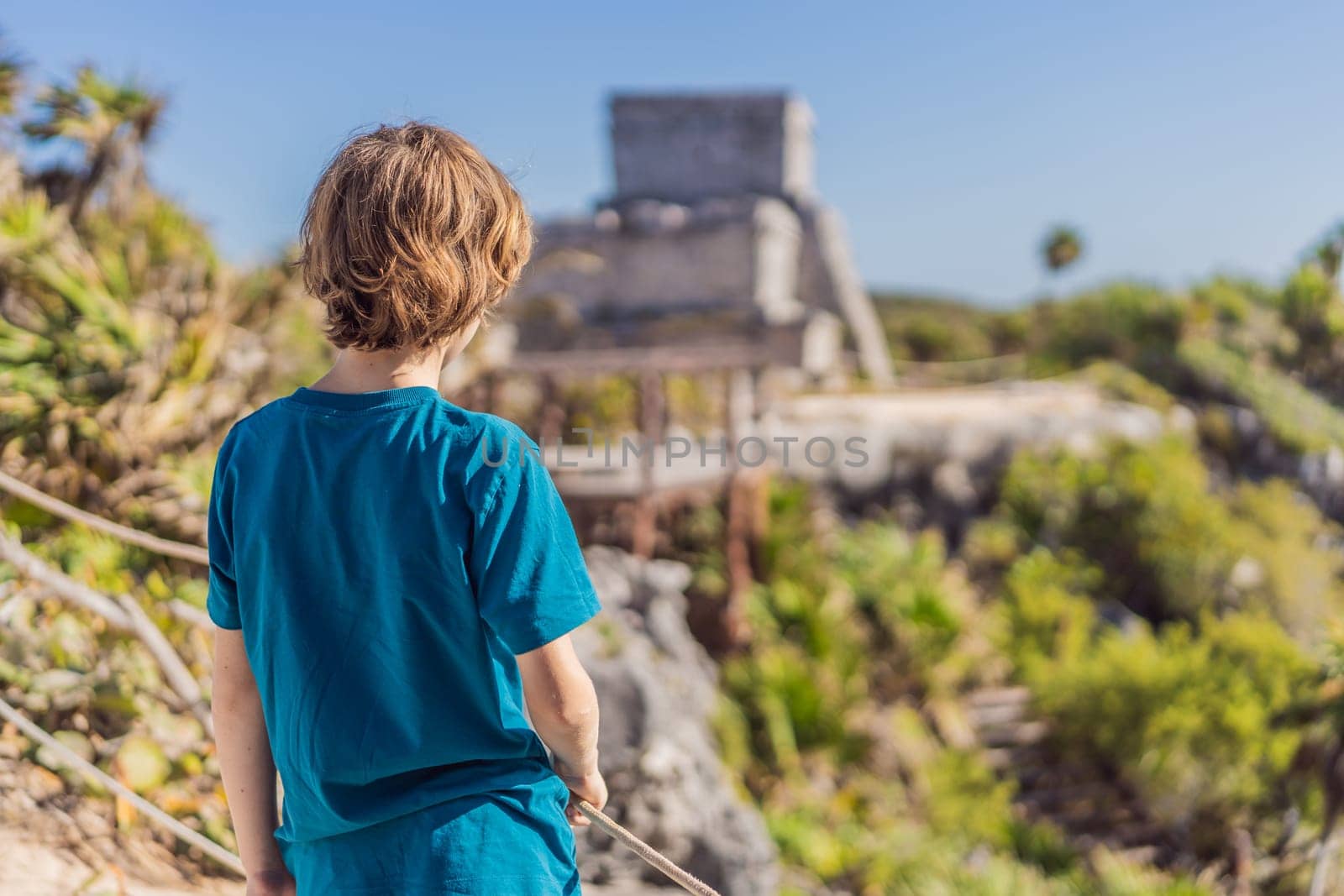 Boy tourist enjoying the view Pre-Columbian Mayan walled city of Tulum, Quintana Roo, Mexico, North America, Tulum, Mexico. El Castillo - castle the Mayan city of Tulum main temple.