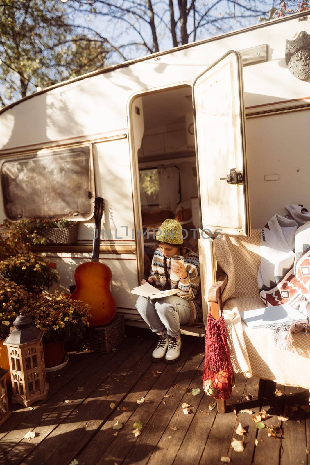 A chic, modern hippie woman enjoys a hot drink on the house terrace, radiating elegance. High quality photo