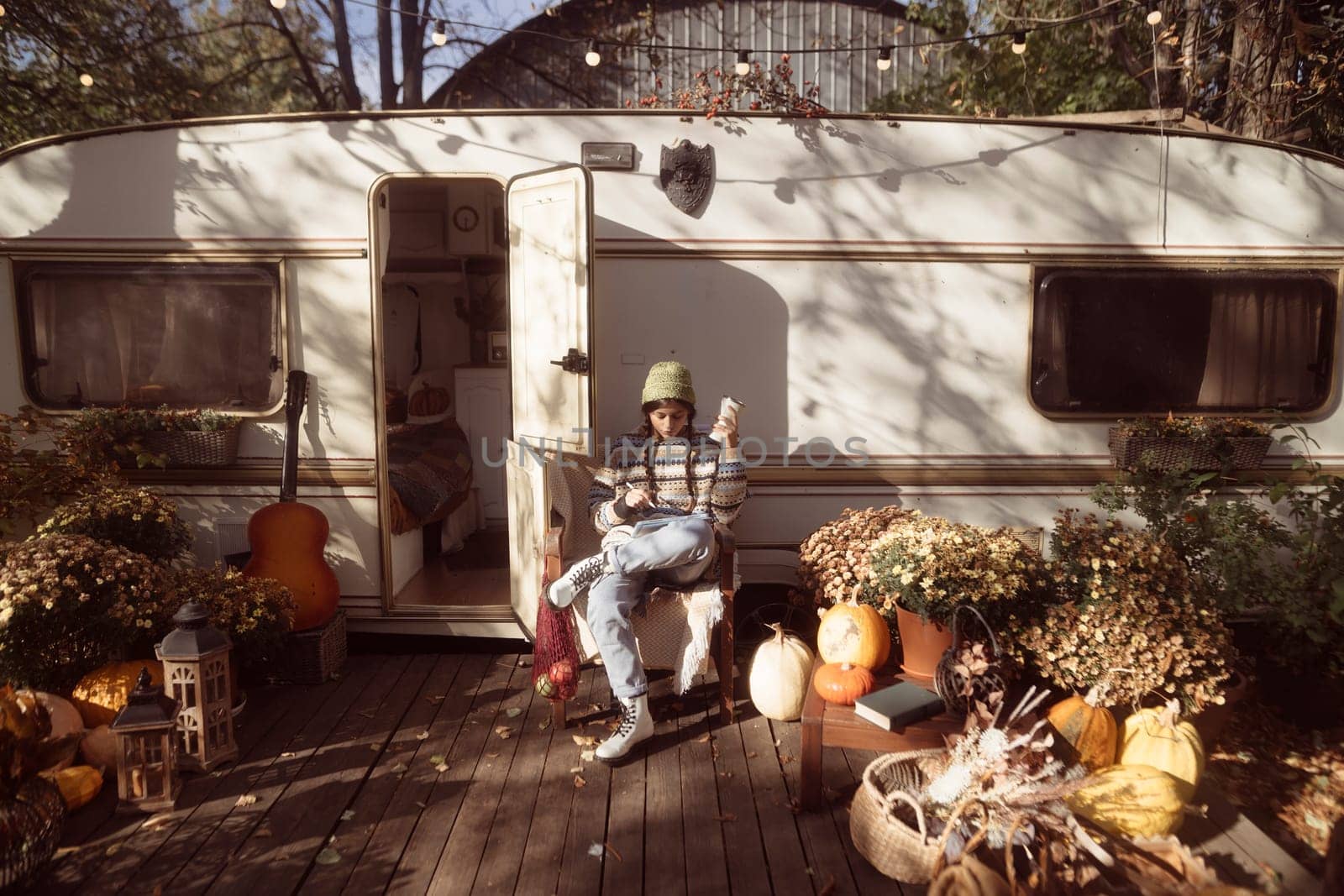 A beautiful girl in a hippie ensemble poses against the backdrop of a trailer in the park. High quality photo