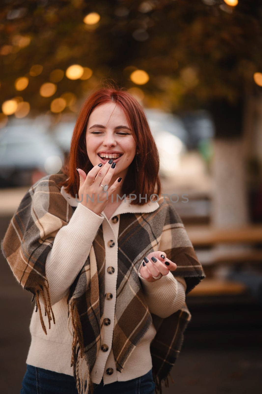 A cheerful redhead beams with joy on the streets of the autumn city. High quality photo