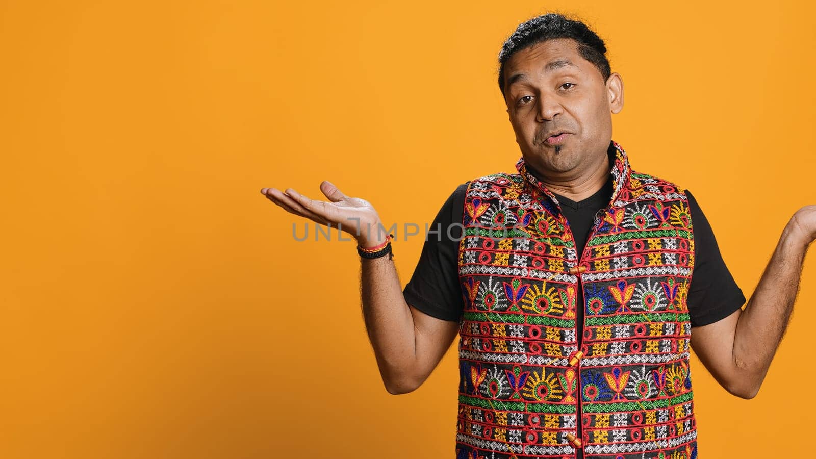 Indian man shrugging shoulders, unable to provide answer, having detached apathy facial expression. Apathetic person doing hand gesturing showing lack of knowledge, studio background, camera A