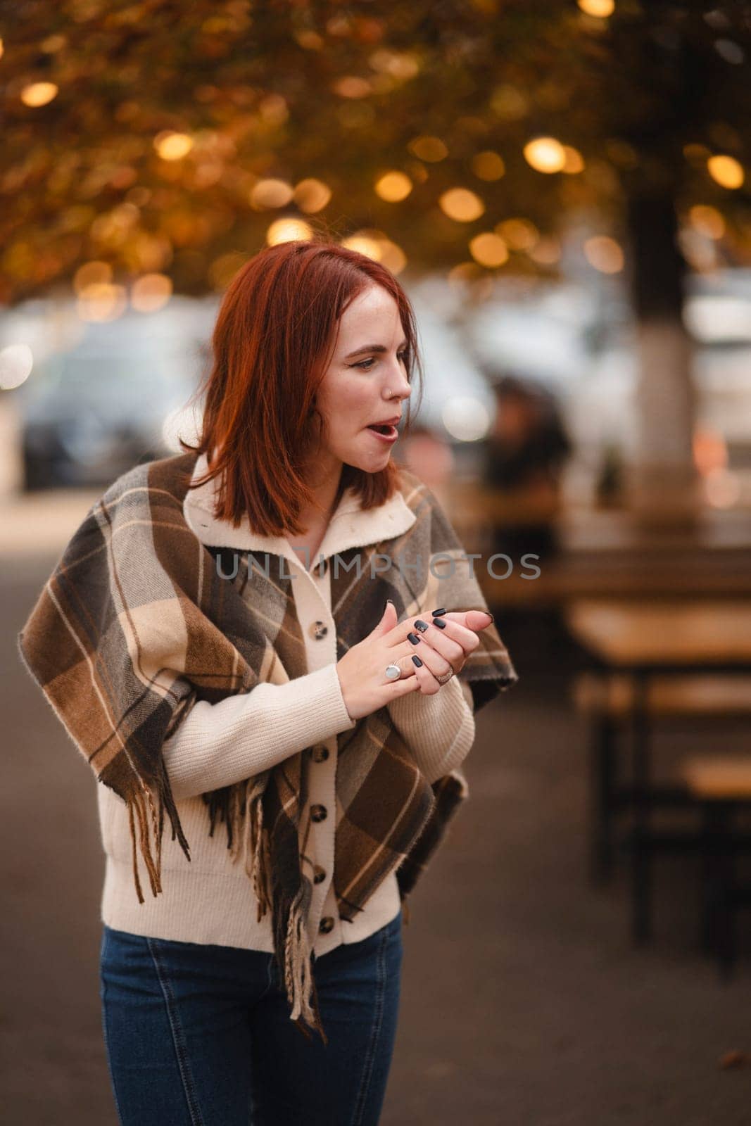 An exuberant redhead glows with laughter, enlivening the autumn city scene. High quality photo