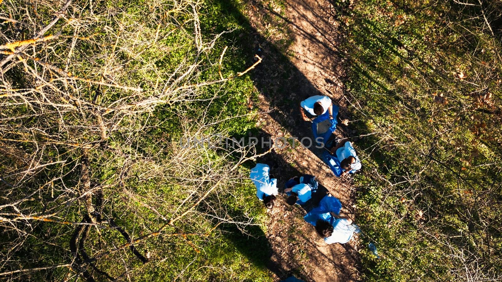 Drone shot of activists team cleaning and recycling garbage in a forest, working on clearing up the woods area for environmental protection. People with ecologic preservation values.