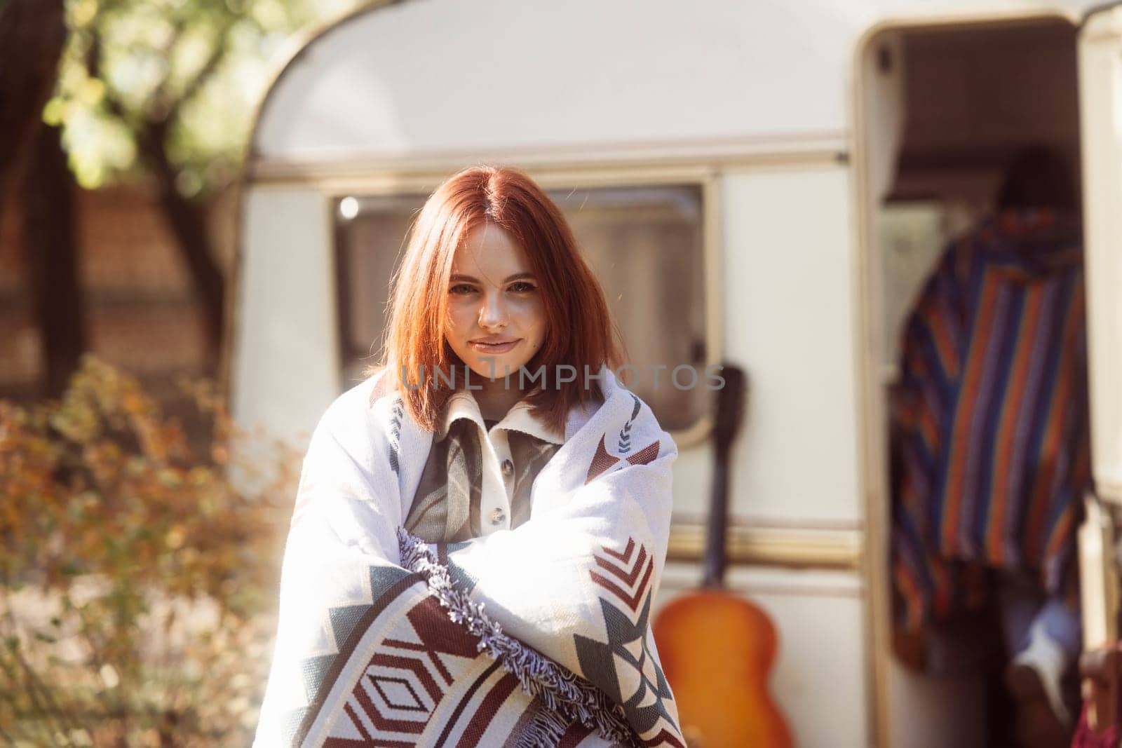 A captivating girl showcases her hippie-inspired look against the park landscape, with a trailer nearby. High quality photo