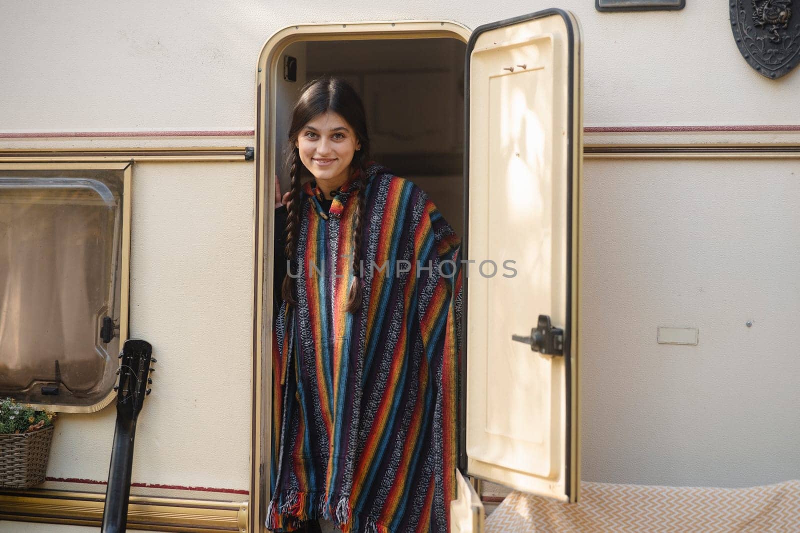 An enchanting lady exudes bohemian vibes against the park scenery, with a trailer in the background. High quality photo