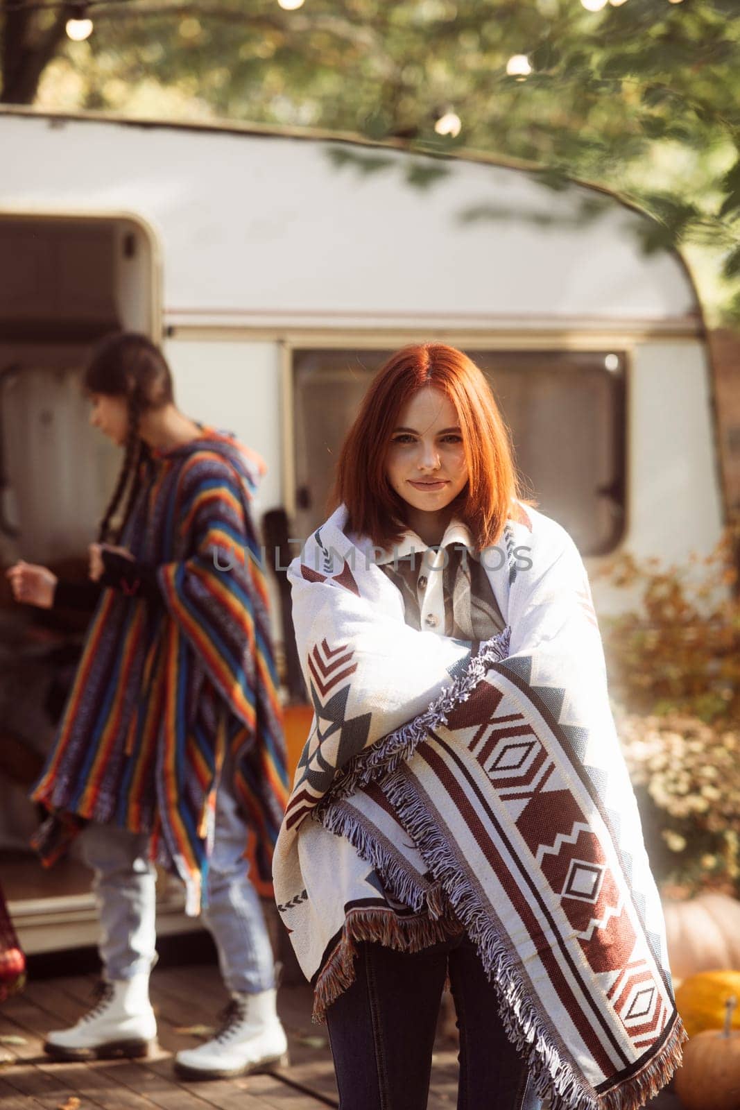 A radiant woman in a hippie outfit poses gracefully against the park backdrop, near a trailer. High quality photo