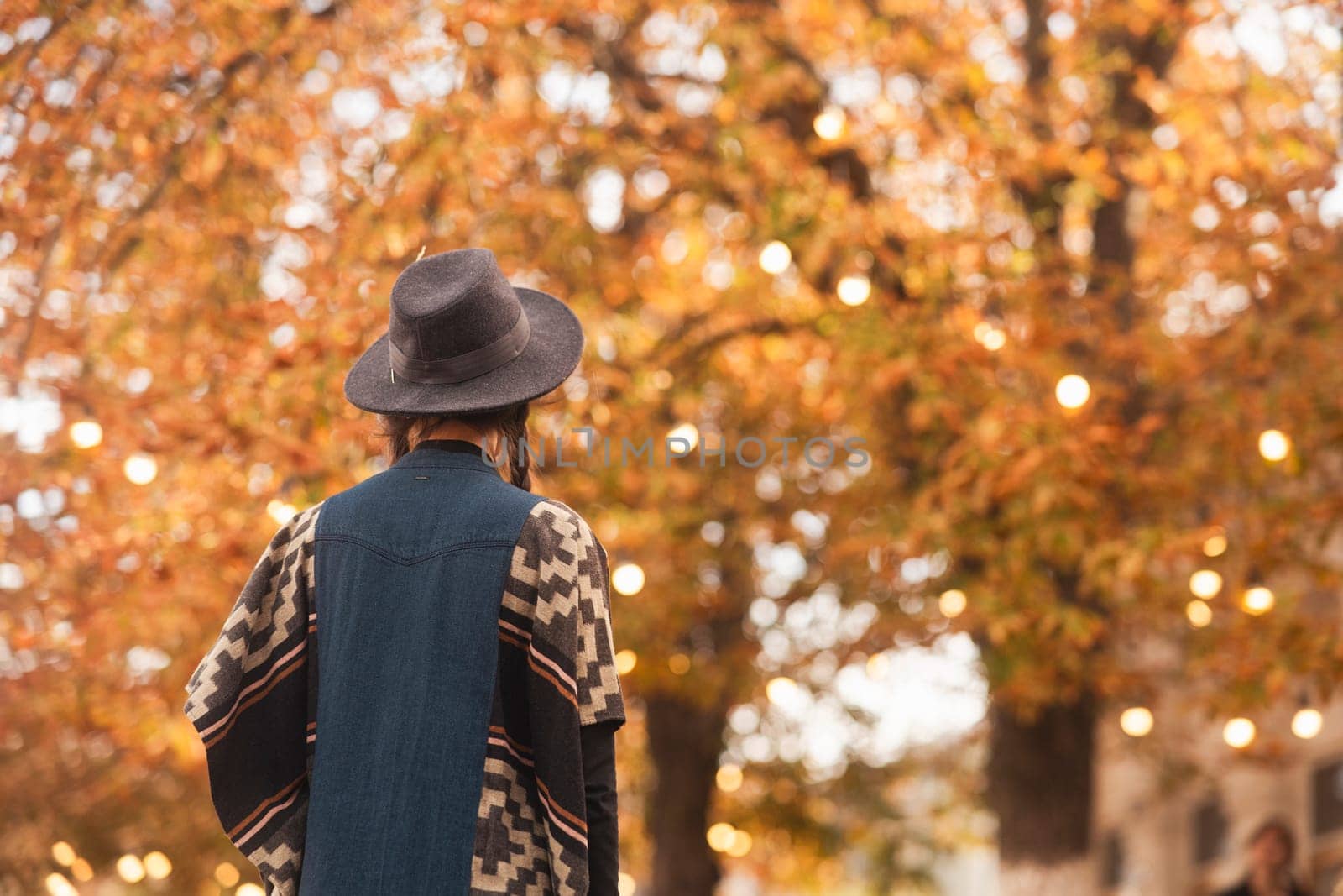 A beautiful girl in boho style, wearing a black hat, wanders through the autumn cityscape. High quality photo