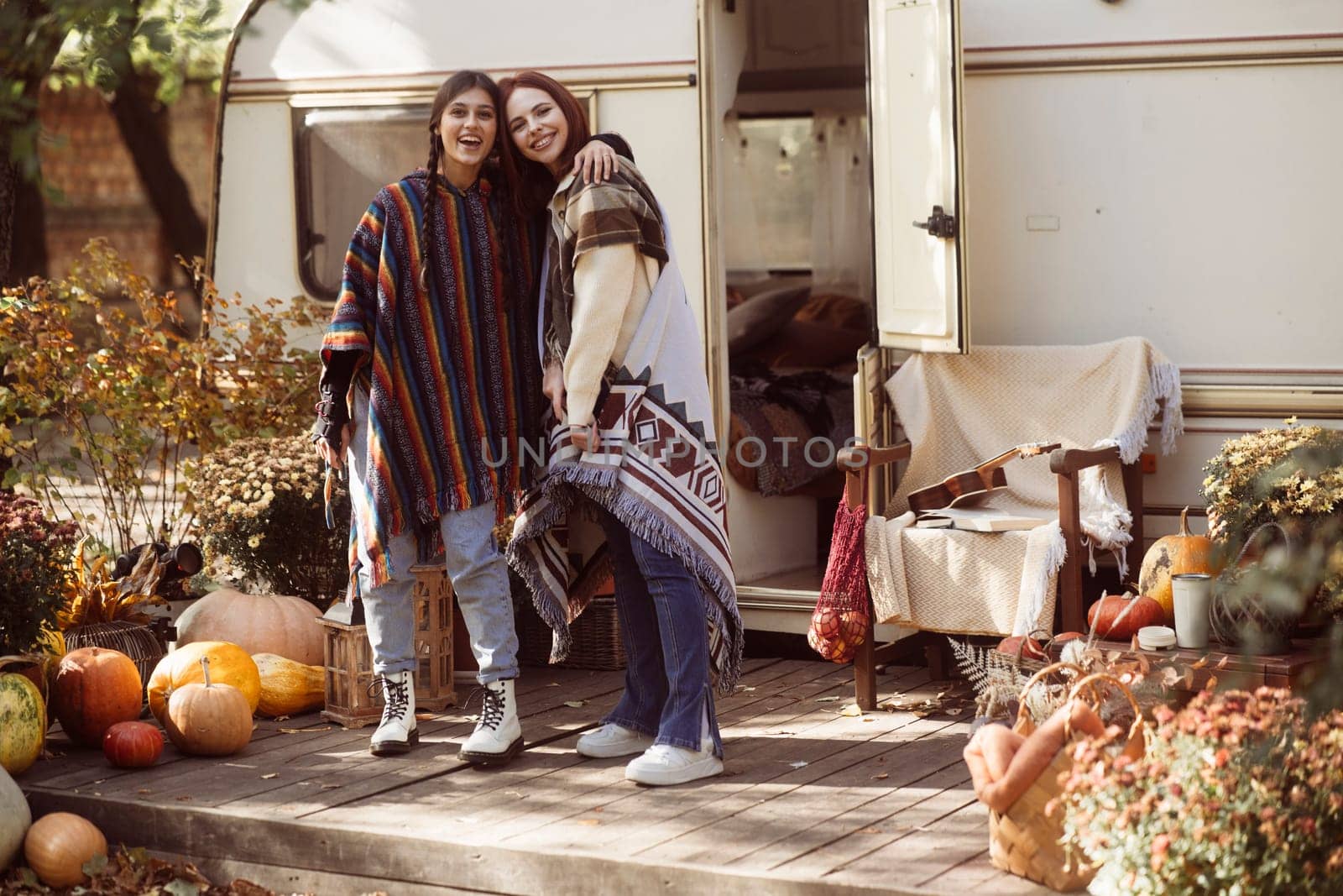 A pair of fashionable young women rock bohemian looks in front of a trailer. High quality photo