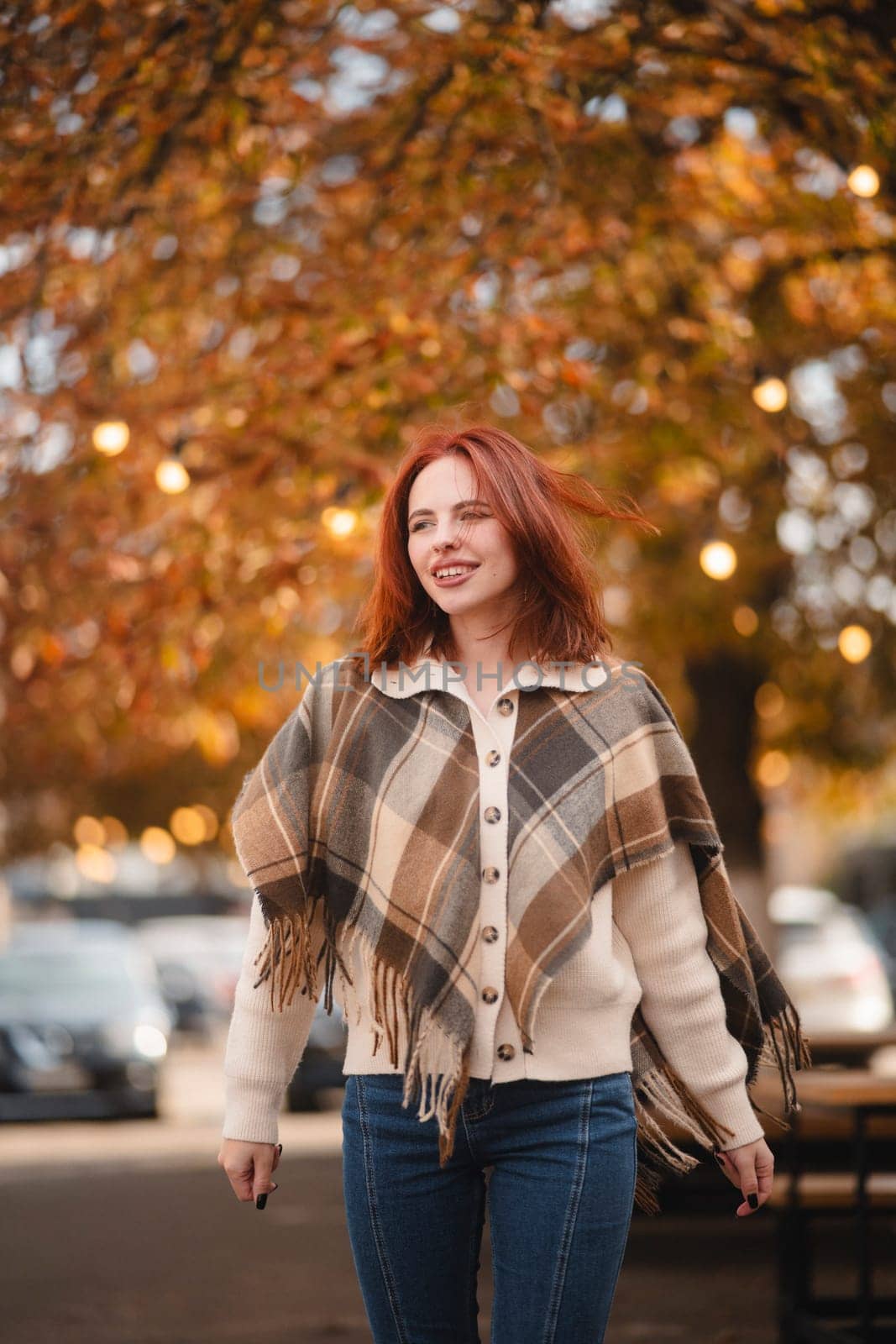 A spirited red-haired girl chuckles joyfully, adding charm to the autumn cityscape. High quality photo