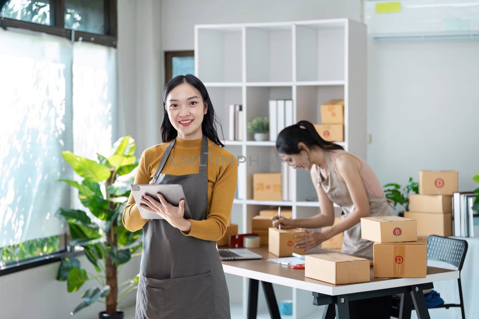 Entrepreneur startup business woman sme holding tablet. Small Online Business Owner, Online Marketing and Product Packing and Delivery Service. E-commerce concept by itchaznong