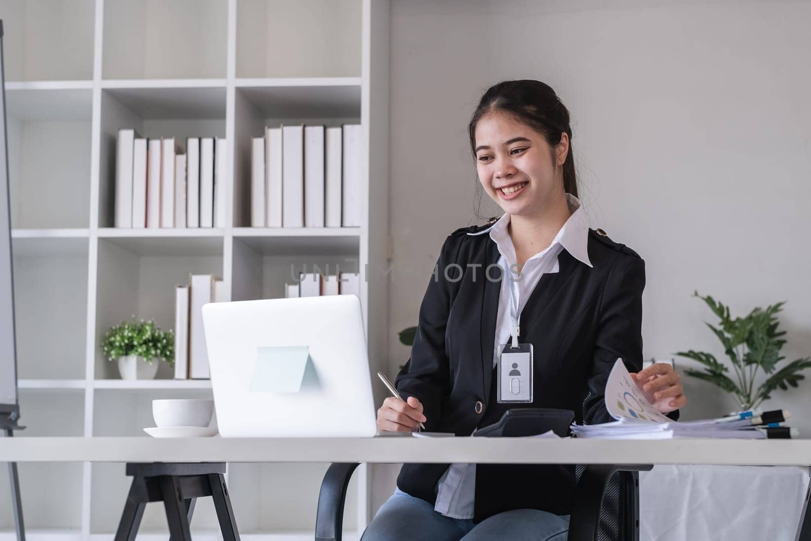 Accountant sitting with financial documents, using laptop, calculating financial and tax figures for company on table in office.