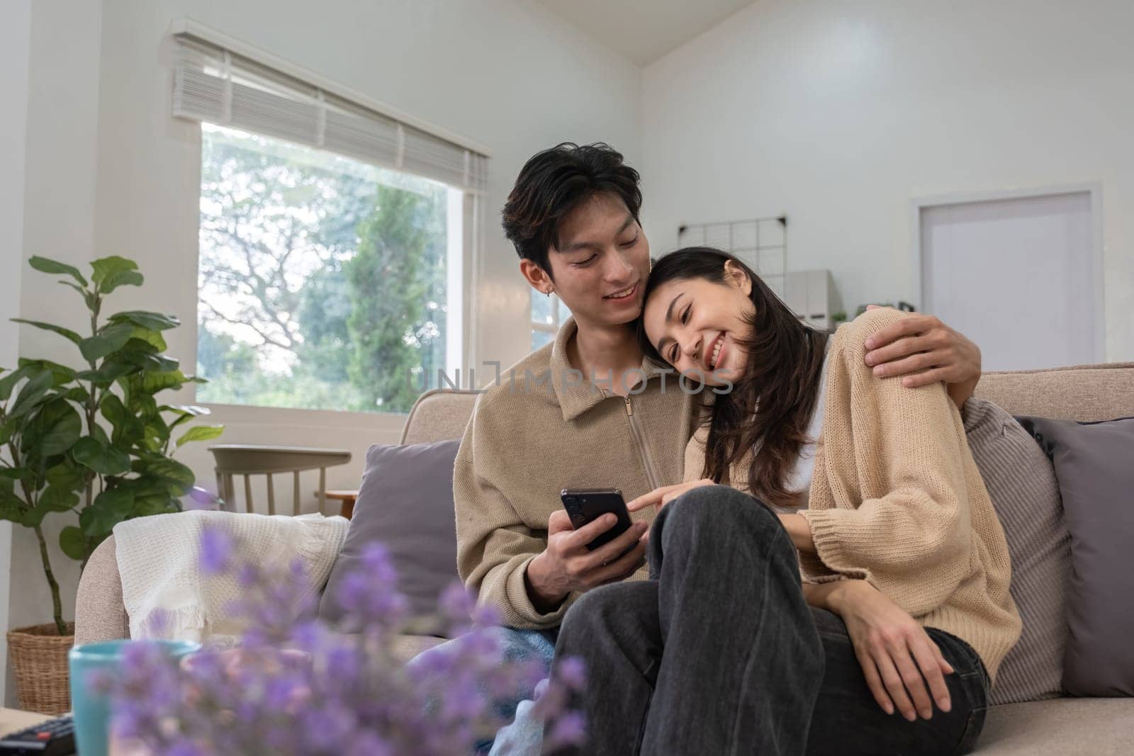 Young Asian couple in love Sitting and relaxing together in the living room happily. Couple making romantic love in the living room.