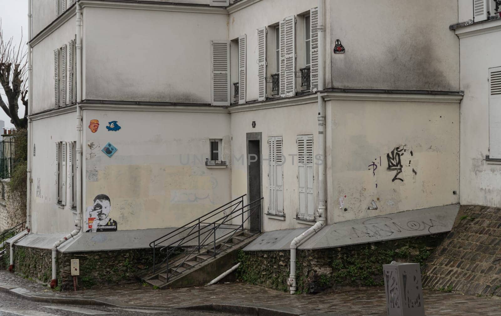 France, Paris - Jan 03, 2024 - Side view of the old house on The historic district of Montmartre in the city of Paris. A narrow cobblestone street with typical French architecture descends and rises, Space for text, Selective focus.