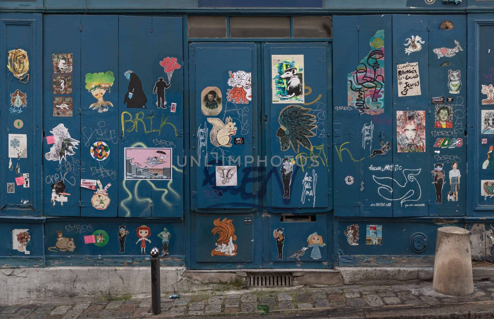 France, Paris - Jan 03, 2024 - A artistic blue metal doorway stickers and graffiti on Montmartre Street. Street art in Paris, Urban intervention art, Paris wall art, Space for text, Selective focus.