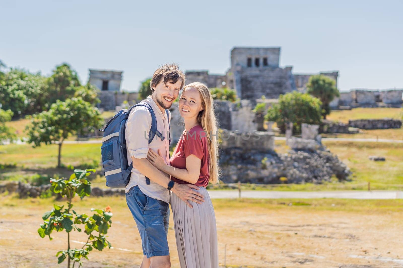 Couple man and woman tourists enjoying the view Pre-Columbian Mayan walled city of Tulum, Quintana Roo, Mexico, North America, Tulum, Mexico. El Castillo - castle the Mayan city of Tulum main temple.