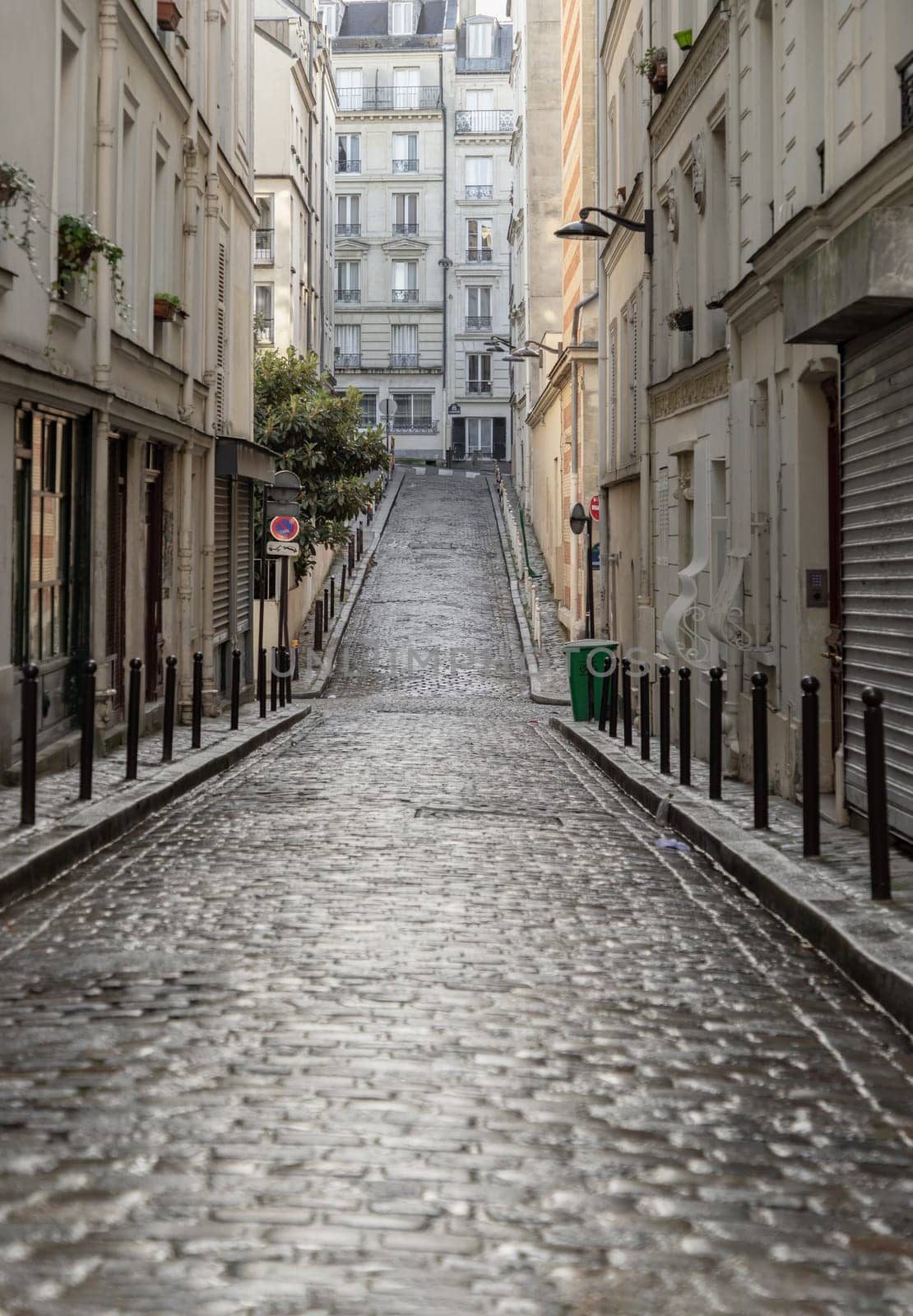 France, Paris - Jan 03, 2024 - Perspective view of one of the old montmartre streets in Paris. A narrow cobblestone street with typical French architecture descends and rises, The historic district of Montmartre in the city of Paris, Space for text,