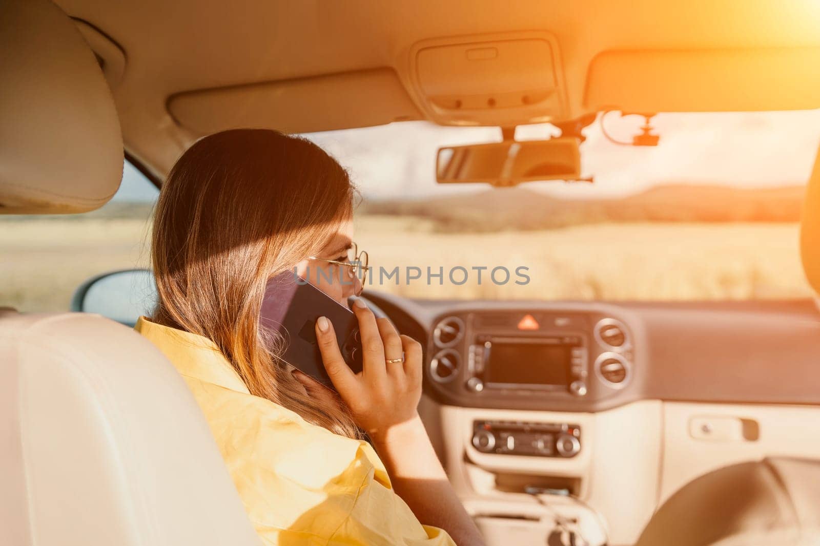 Happy woman talking on the phone while sitting in the car on nature Relaxed video call, professional conversation, female executive in automobile. business woman talking on video call on phone. by panophotograph