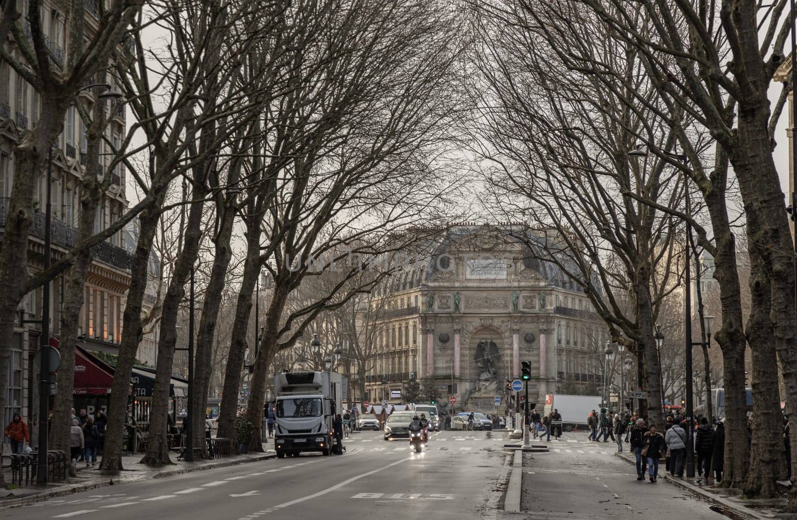 France, Paris - Jan 03, 2024 - Street view and Old building design of The Fontaine Saint-Michel in City of Paris. Traffic on the road with cars and people, Space for text, Selective focus.