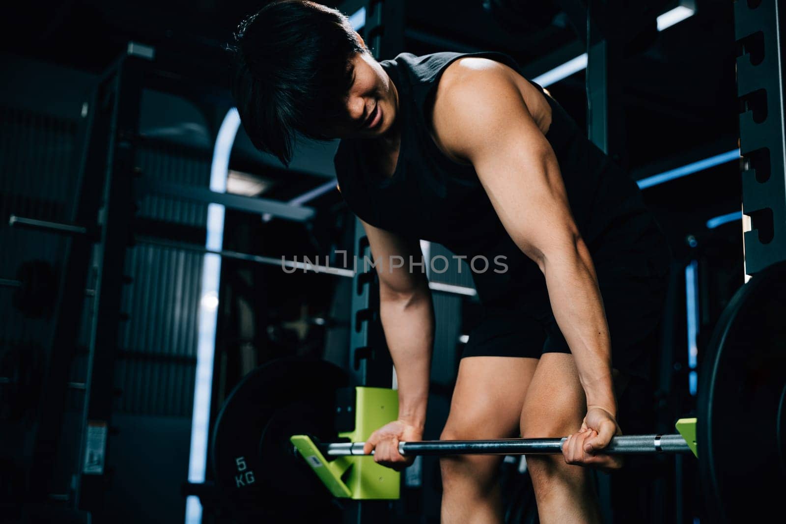 A handsome Asian man holding a barbell and lifting weights for a strength-building workout that showcases his athletic body and determination. power lifting training concept