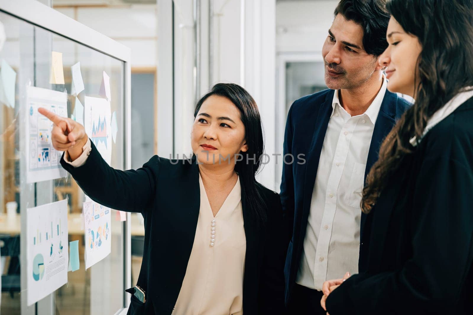 Engaging in teamwork-focused meeting, colleagues actively participate in brainstorming sessions and discussions around whiteboard. Emphasizing effective collaboration conversations, and feedback. by Sorapop