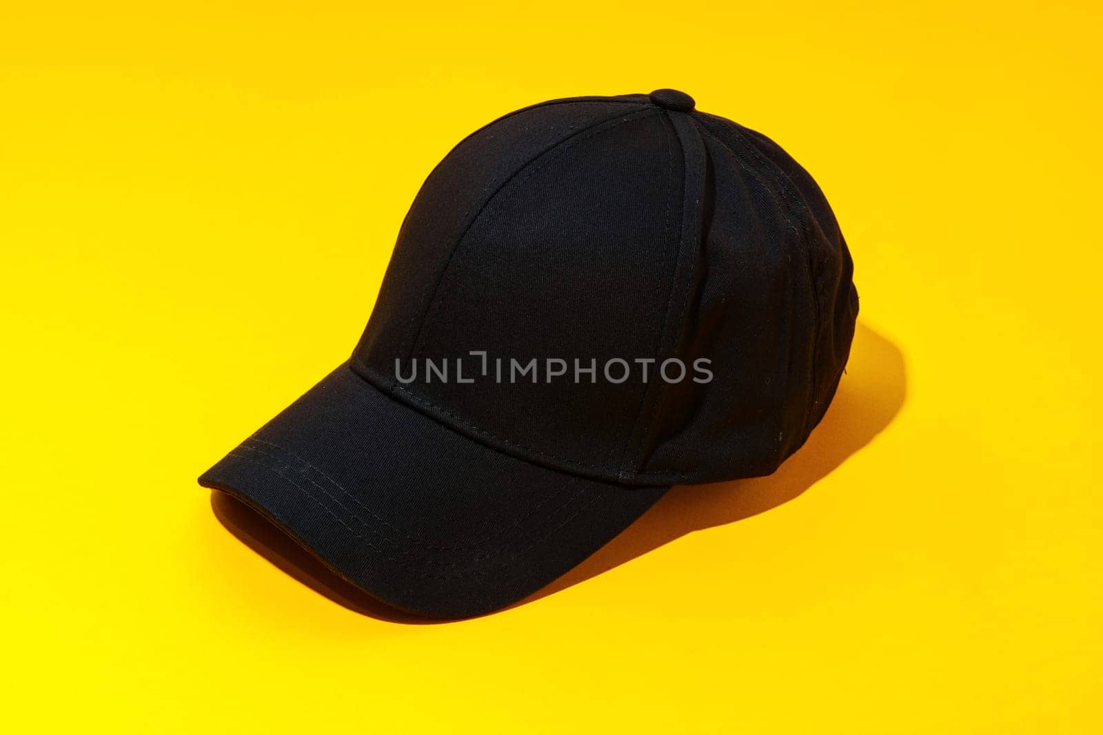 Baseball hat against yellow background in studio close up