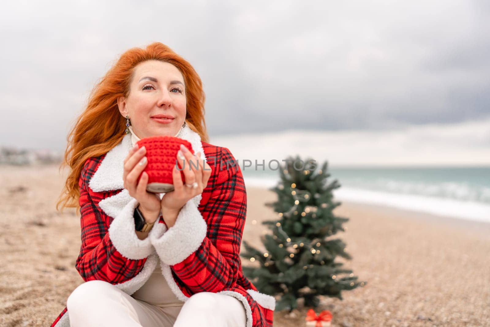 Lady in plaid shirt with a red mug in her hands enjoys beach with Christmas tree. Coastal area. Christmas, New Year holidays concep by Matiunina