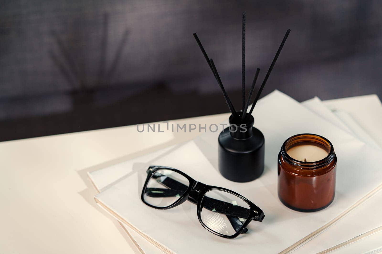 Aromatic reed freshener and candle on table in room close up