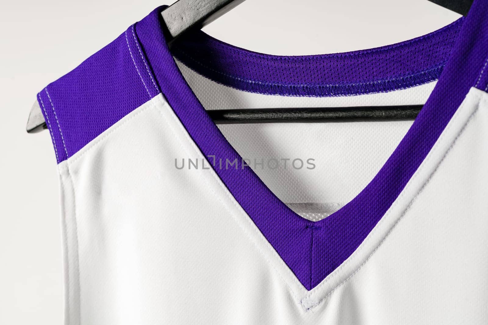 White basketball jersey hanging against white background close up