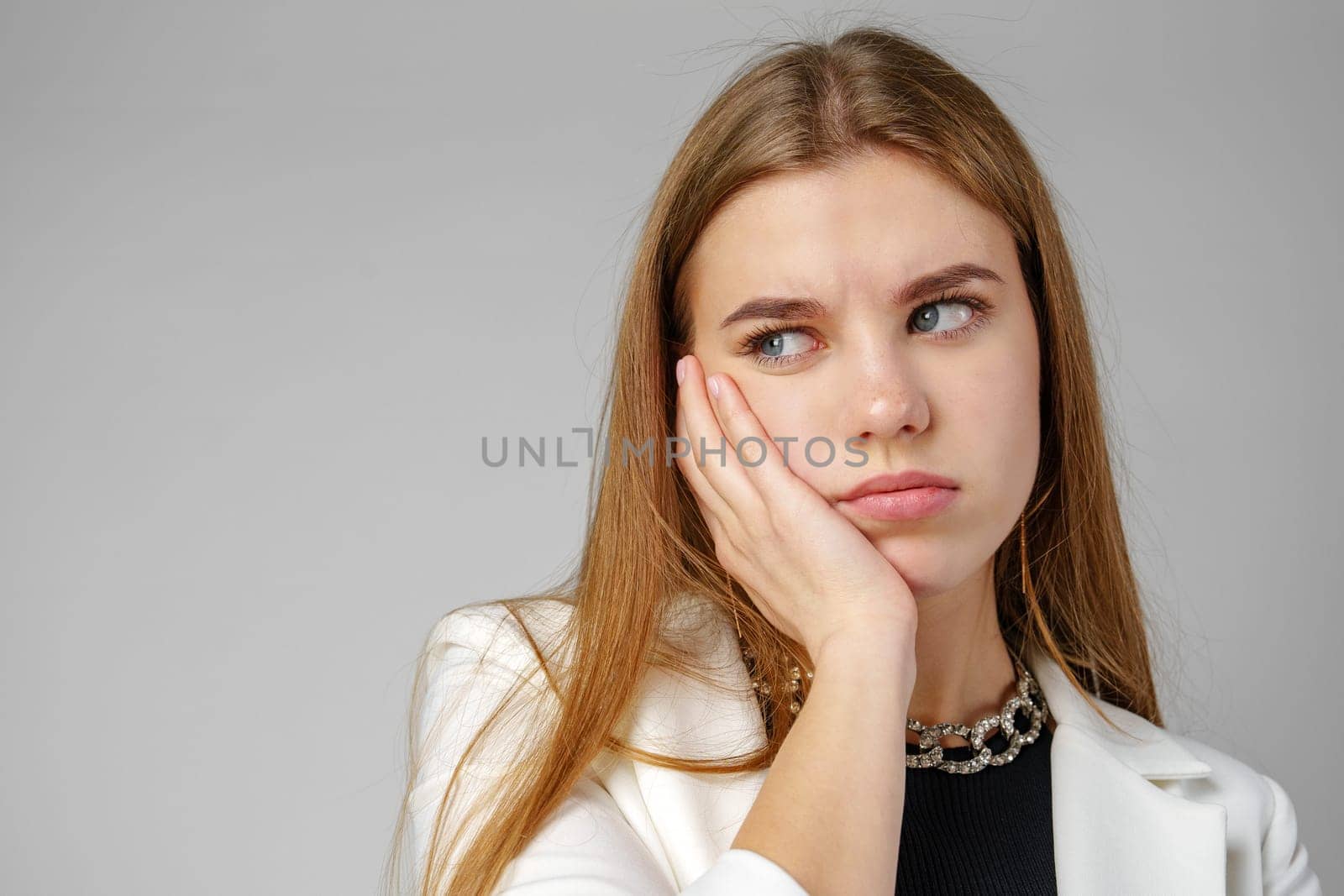 Young Woman Expressing Discontent against gray background in studio