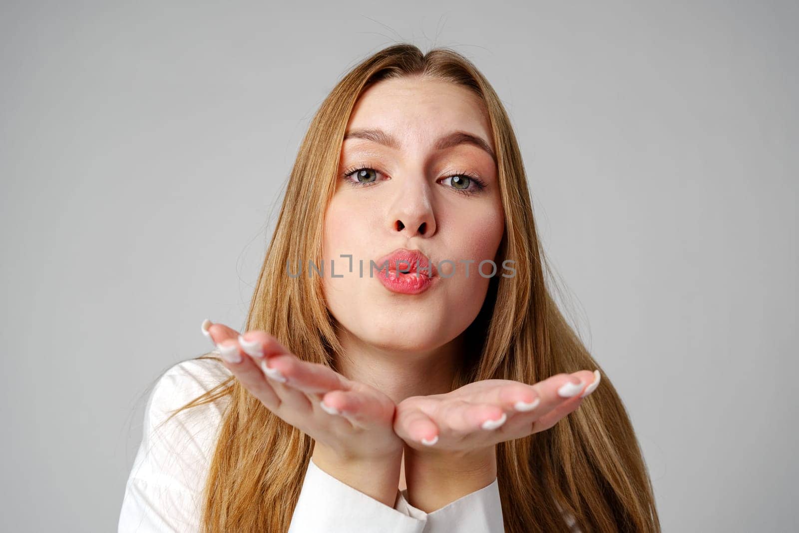 Young Woman Blowing a Kiss Towards the Camera in a Studio by Fabrikasimf