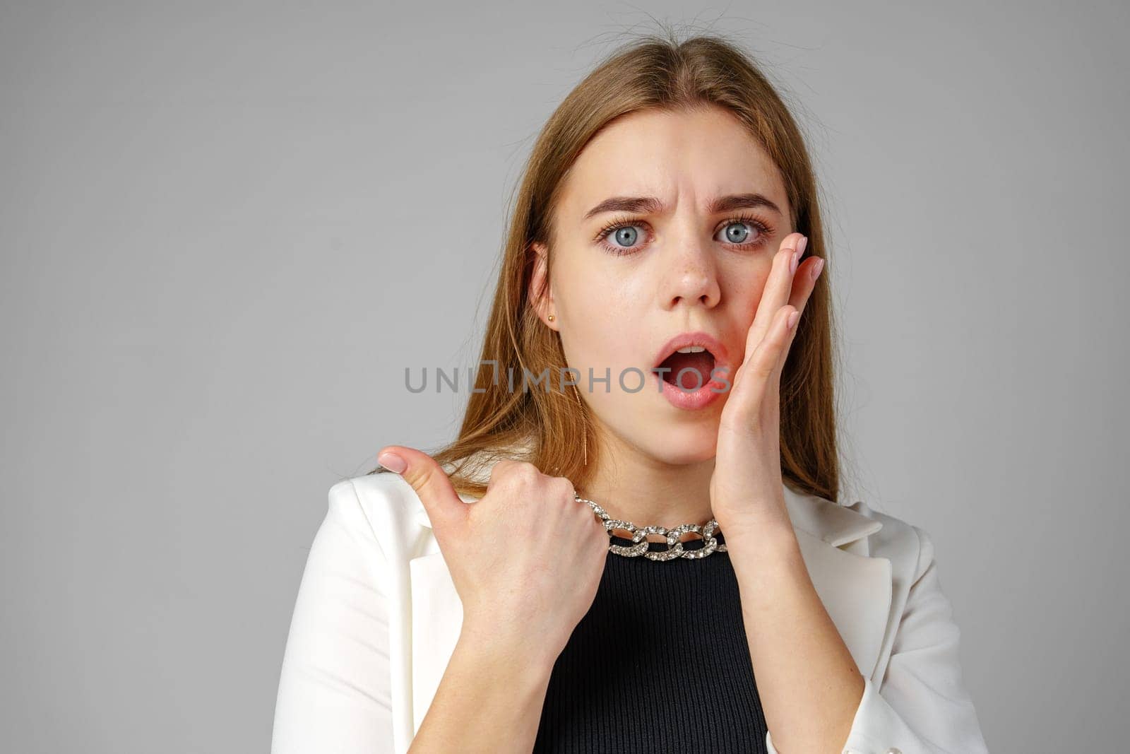 Confident Young Businesswoman Presenting With Hand Gesture in Studio Setting copy space