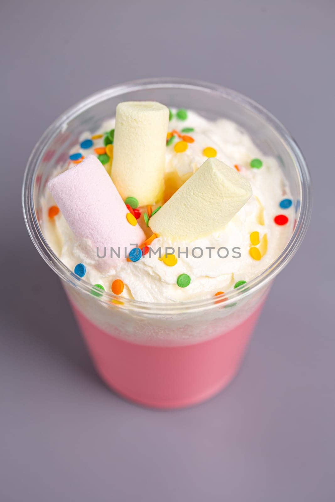 pink milkshake with marshmallow in a plastic cup.