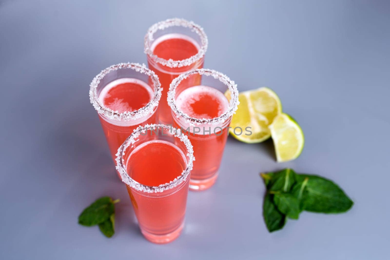 four pink cocktails with lime and mint top view by Pukhovskiy