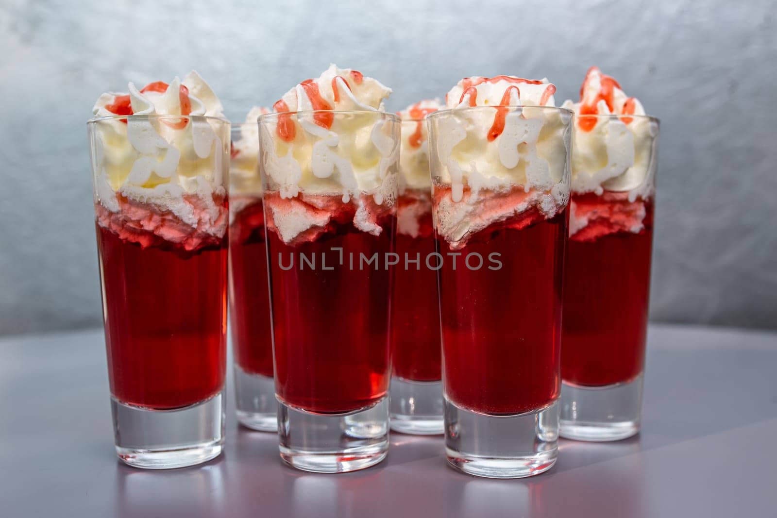 set of red cocktails with cream on a gray background by Pukhovskiy