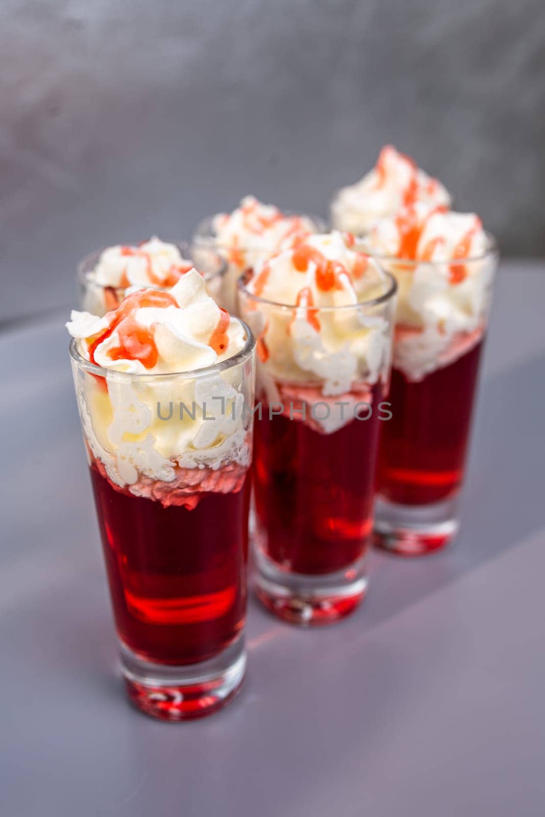 three red alcoholic cocktails with cream in the shot