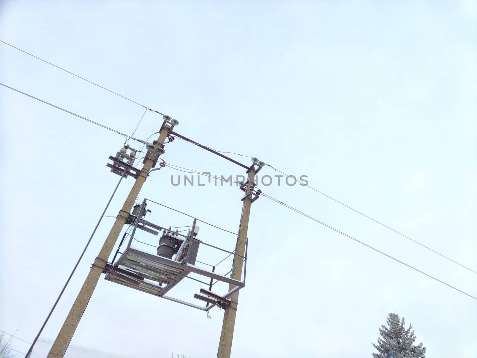 Old power line pole and transformer against blue sky in sunny day by keleny