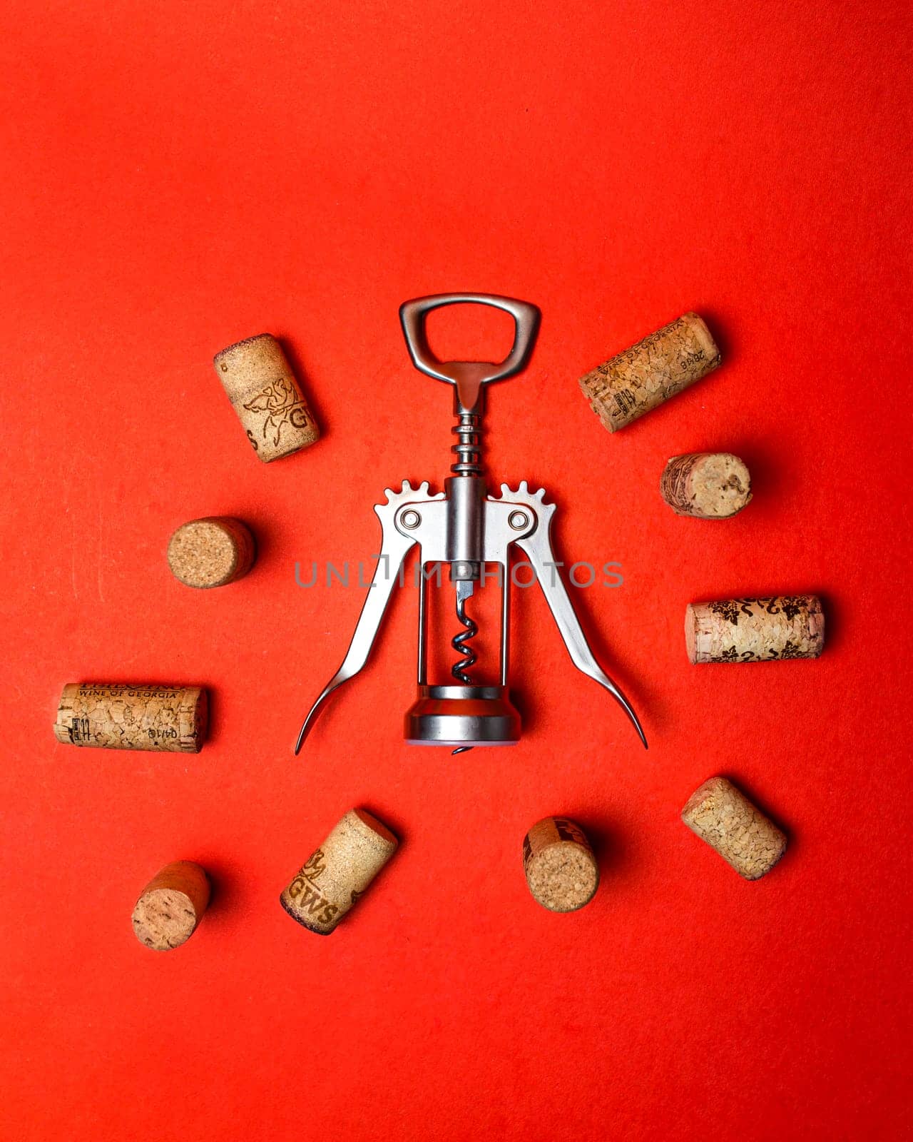 metal corkscrew with wine corks on a red background.