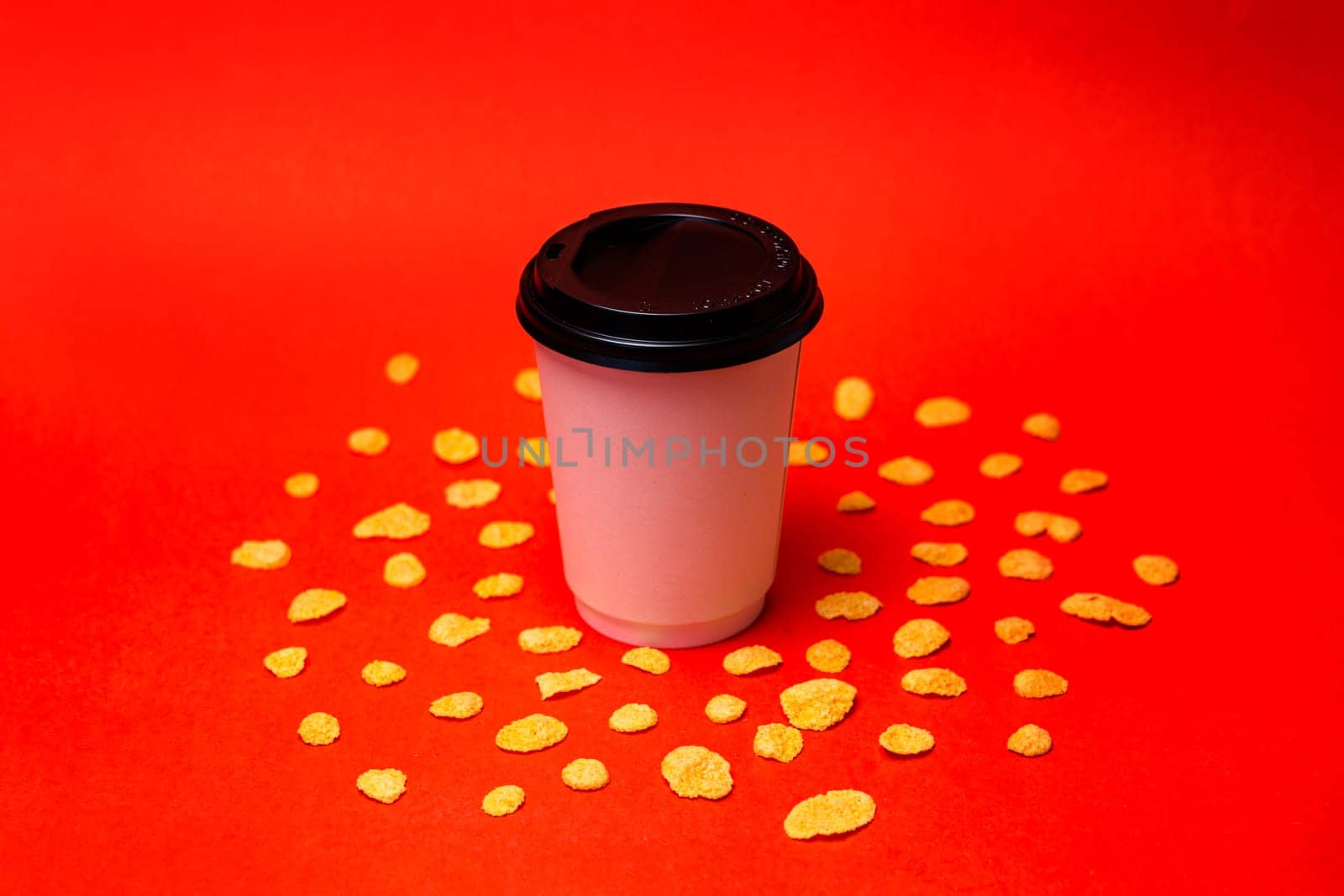 white cup of coffee with corn flakes on a red background.