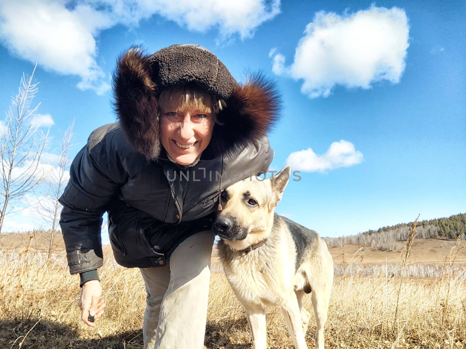 Adult girl or middle aged woman with shepherd dog in an autumn day