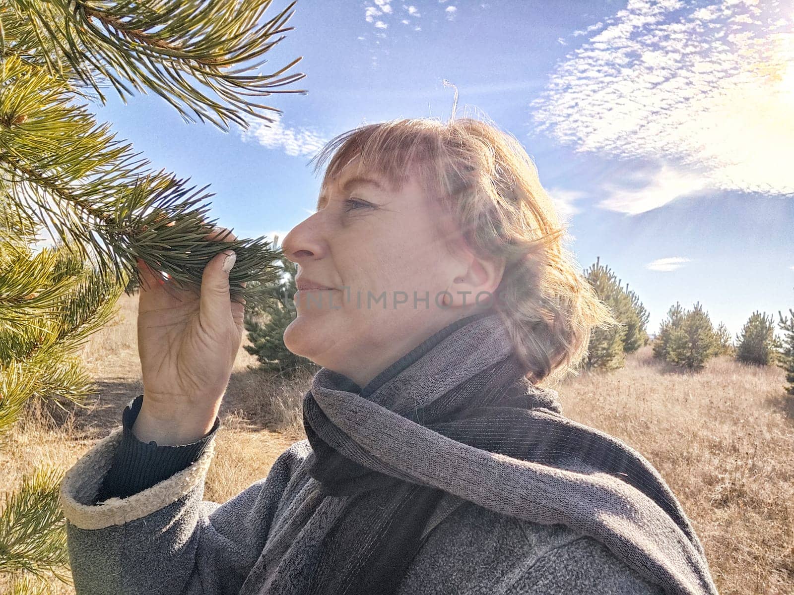 Happy female blonde tourist taking selfie picture outside. Middle aged mature woman having fun on an adventure trip on nature