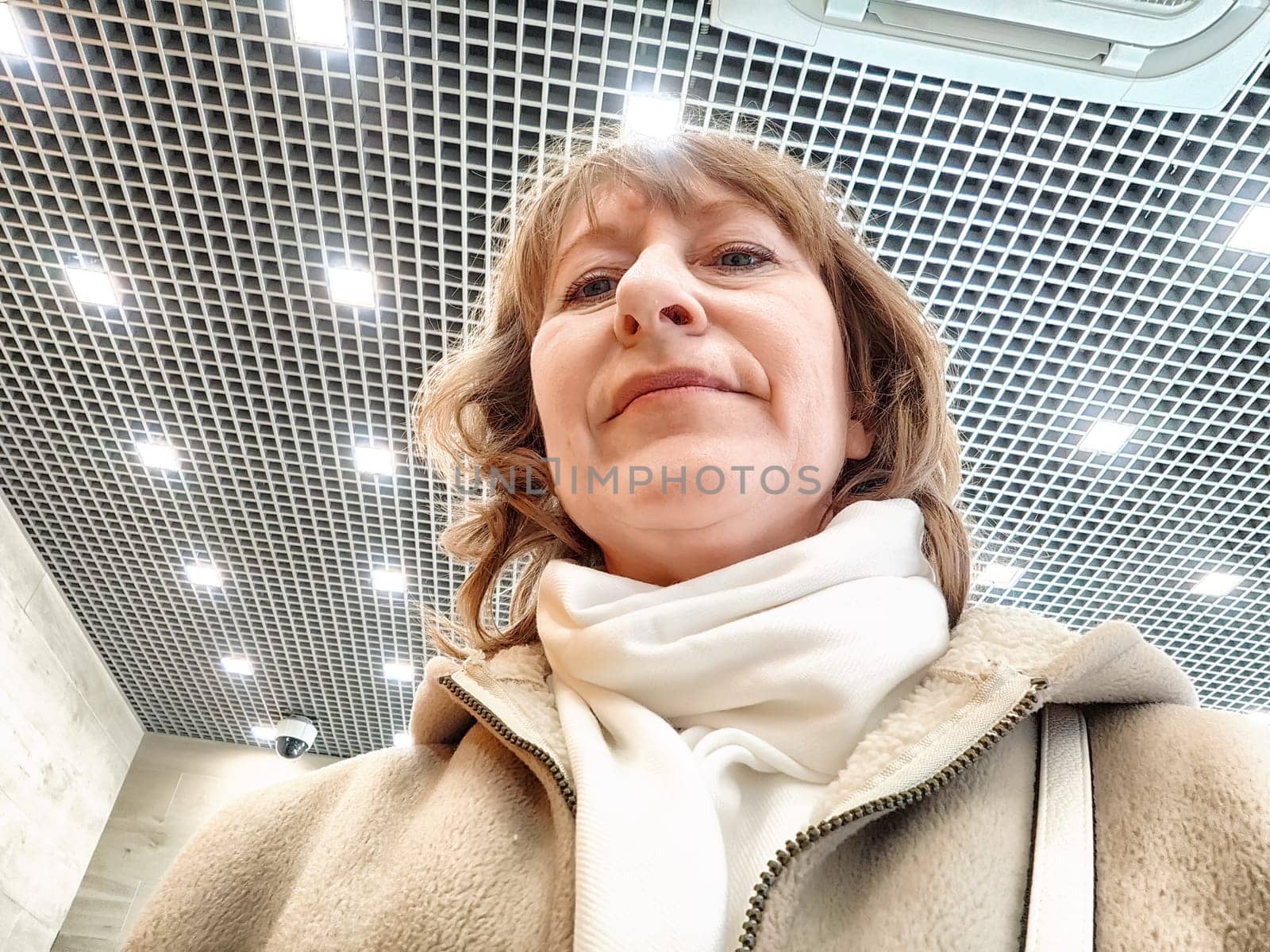 Middle-Aged Woman Captures Selfie While Shopping Indoors. Smiling adult shopper takes a self-portrait during an indoor shopping trip by keleny