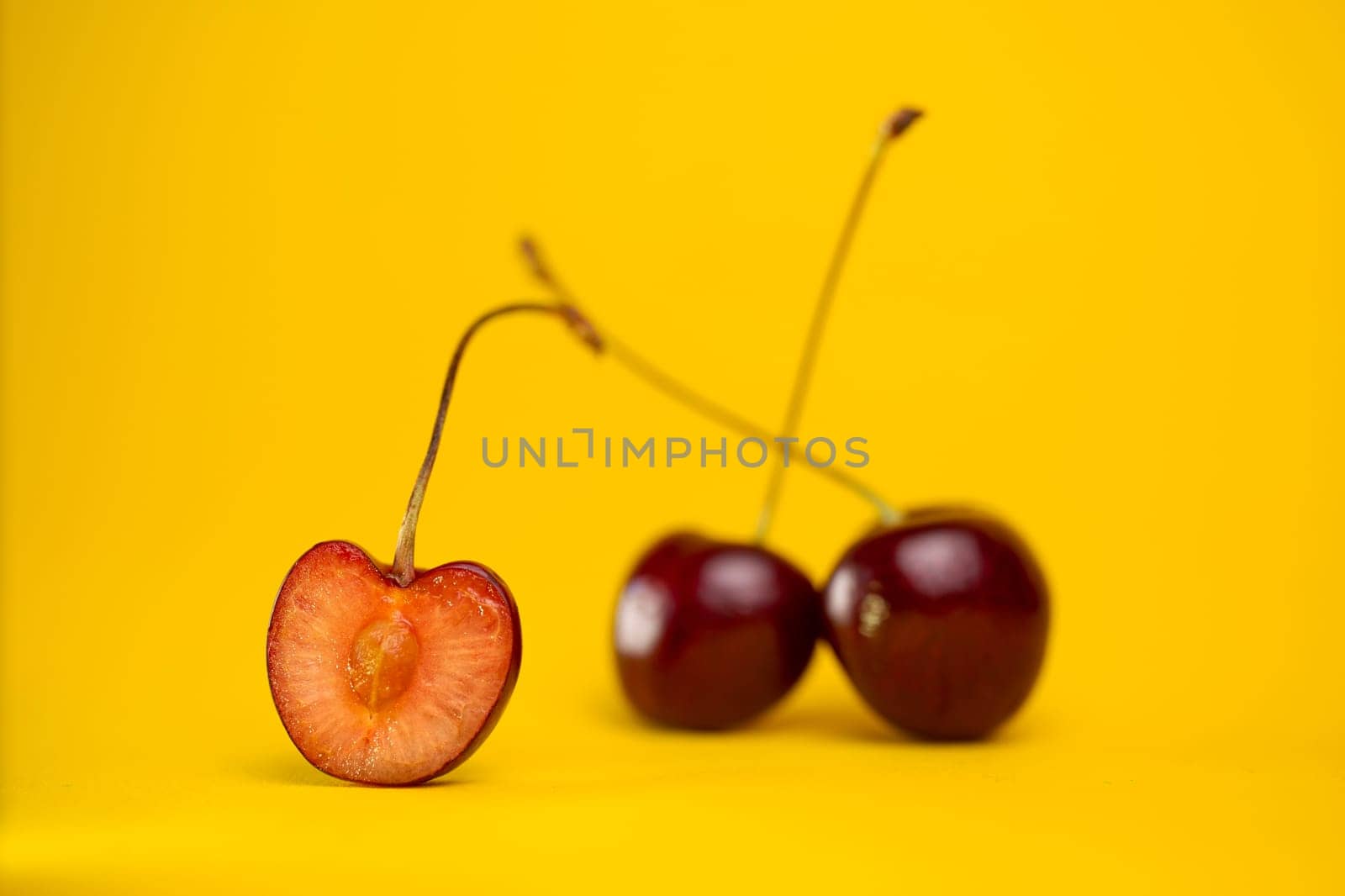 ripe cherries in a section on a yellow background by Pukhovskiy