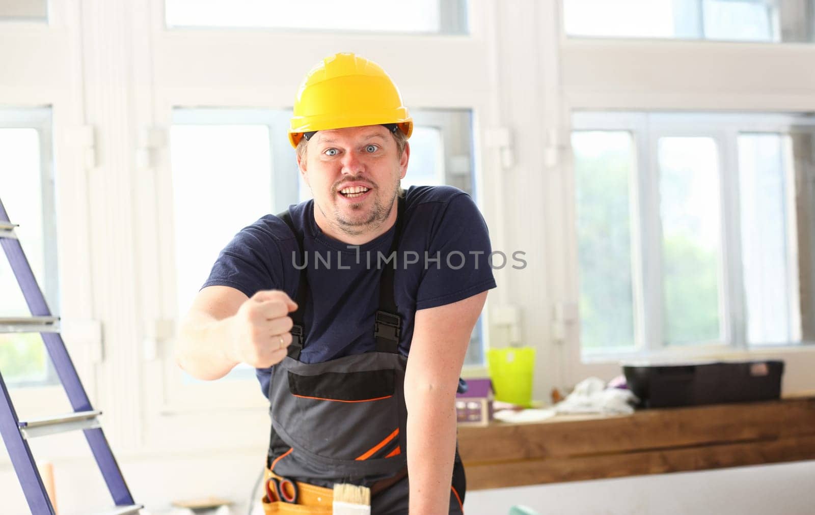 Smiling funny worker in yellow helmet posing by kuprevich