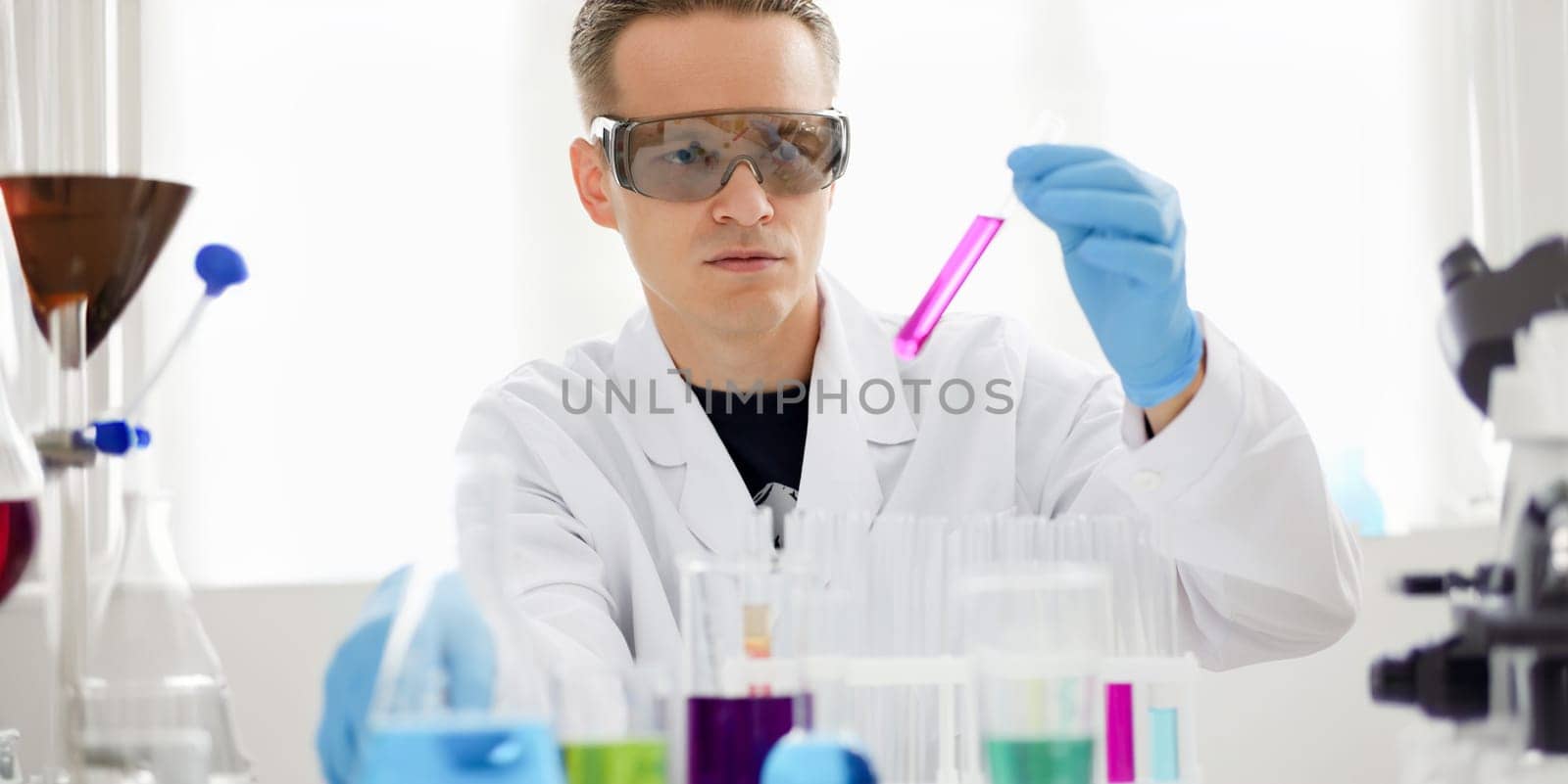 A male chemist holds test tube of glass in by kuprevich