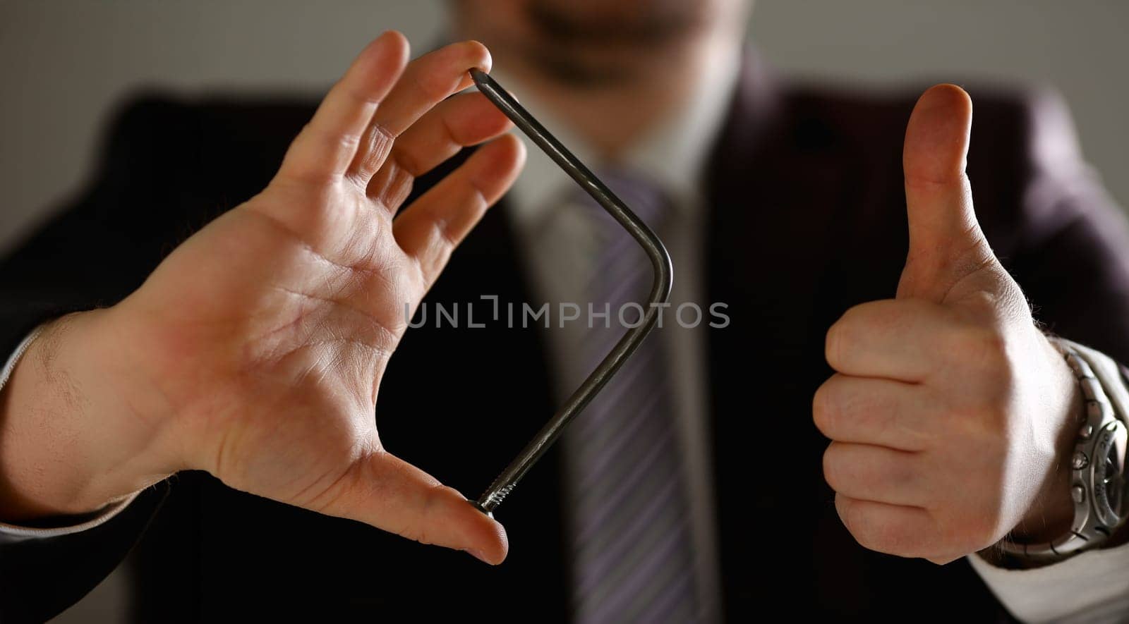 Man in suit and tie bend nail with arms closeup by kuprevich