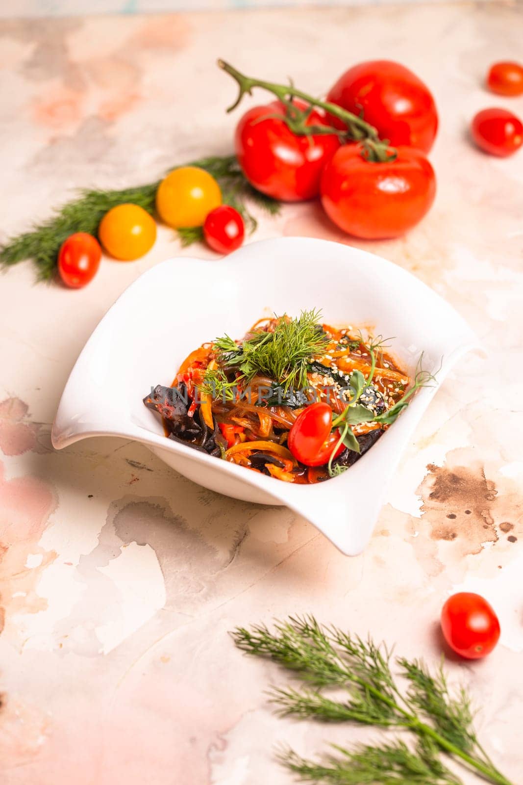 A delicious and healthy meal of Japchae, made with sweet potato noodles, vegetables, and a savory sauce, garnished with tomatoes and dill