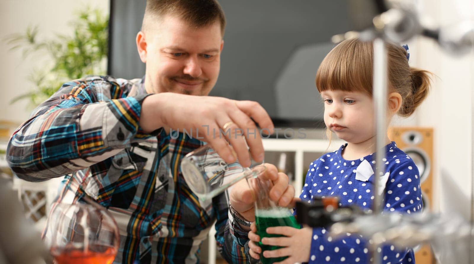 Man and little girl play with colourful liquids portrait. Young team clean research equipment colour reagent food additions flavor activity flavour concept