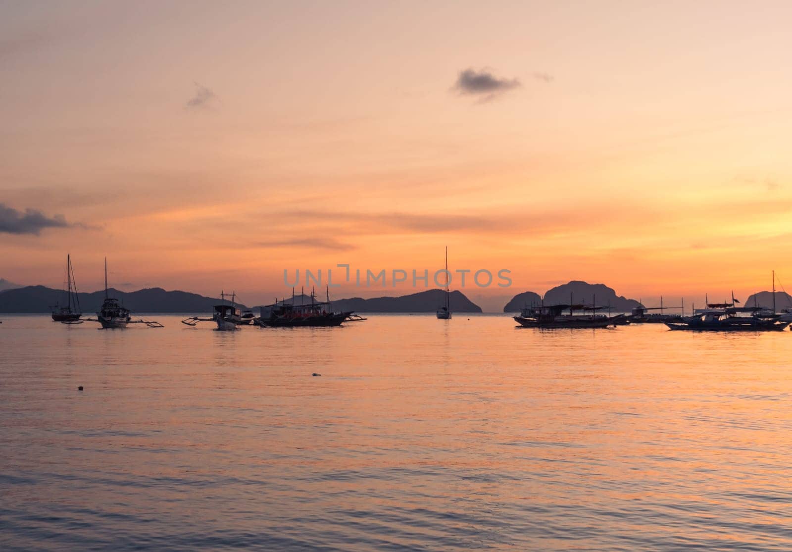 Boats anchored in a calm bay at sunset near scenic islands. Philippines, Palawan. by Busker